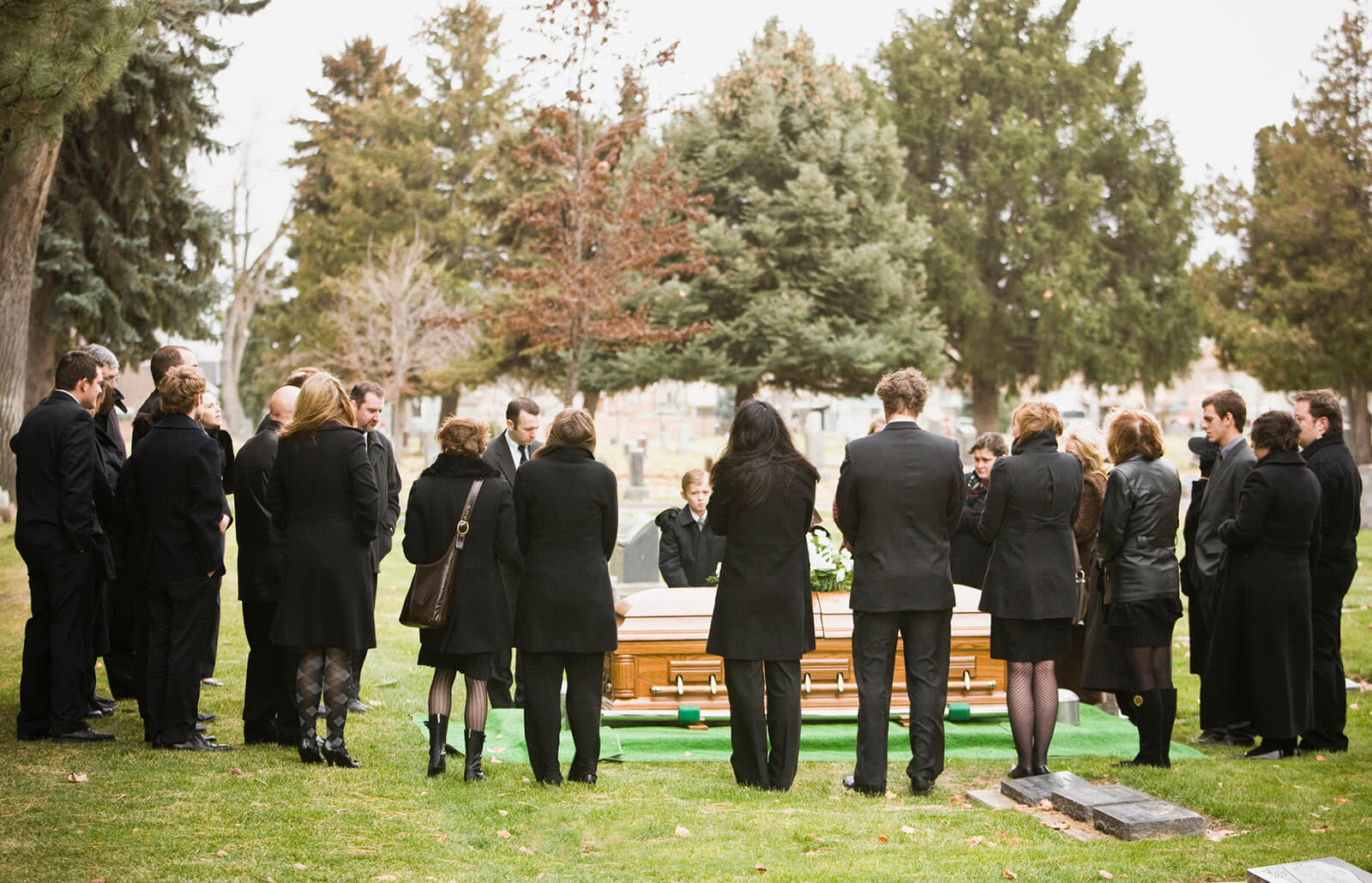 mourners surround a coffin at a graveside