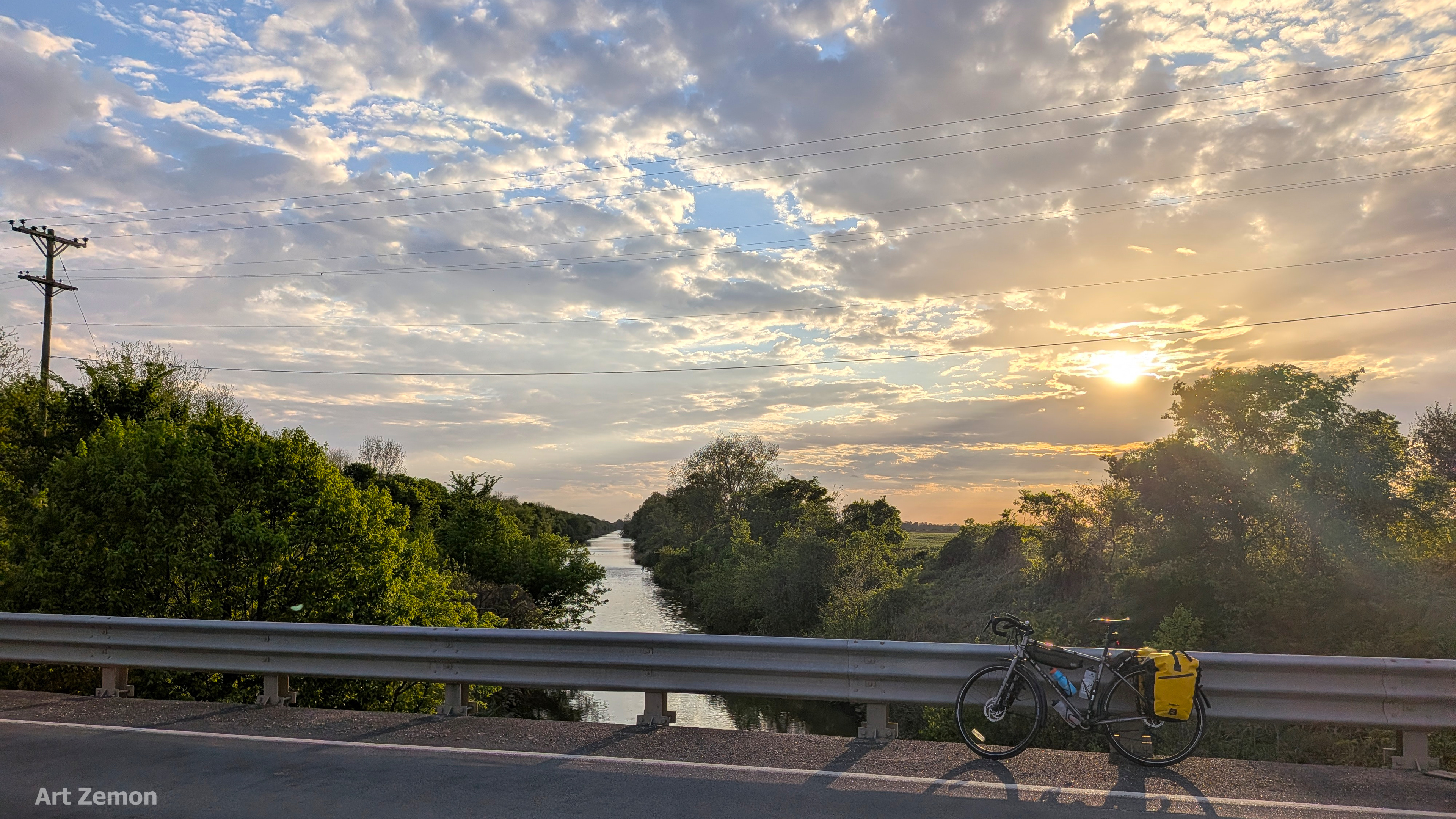touring bicycle parked on a bridge with a dramatic setting sun in the background