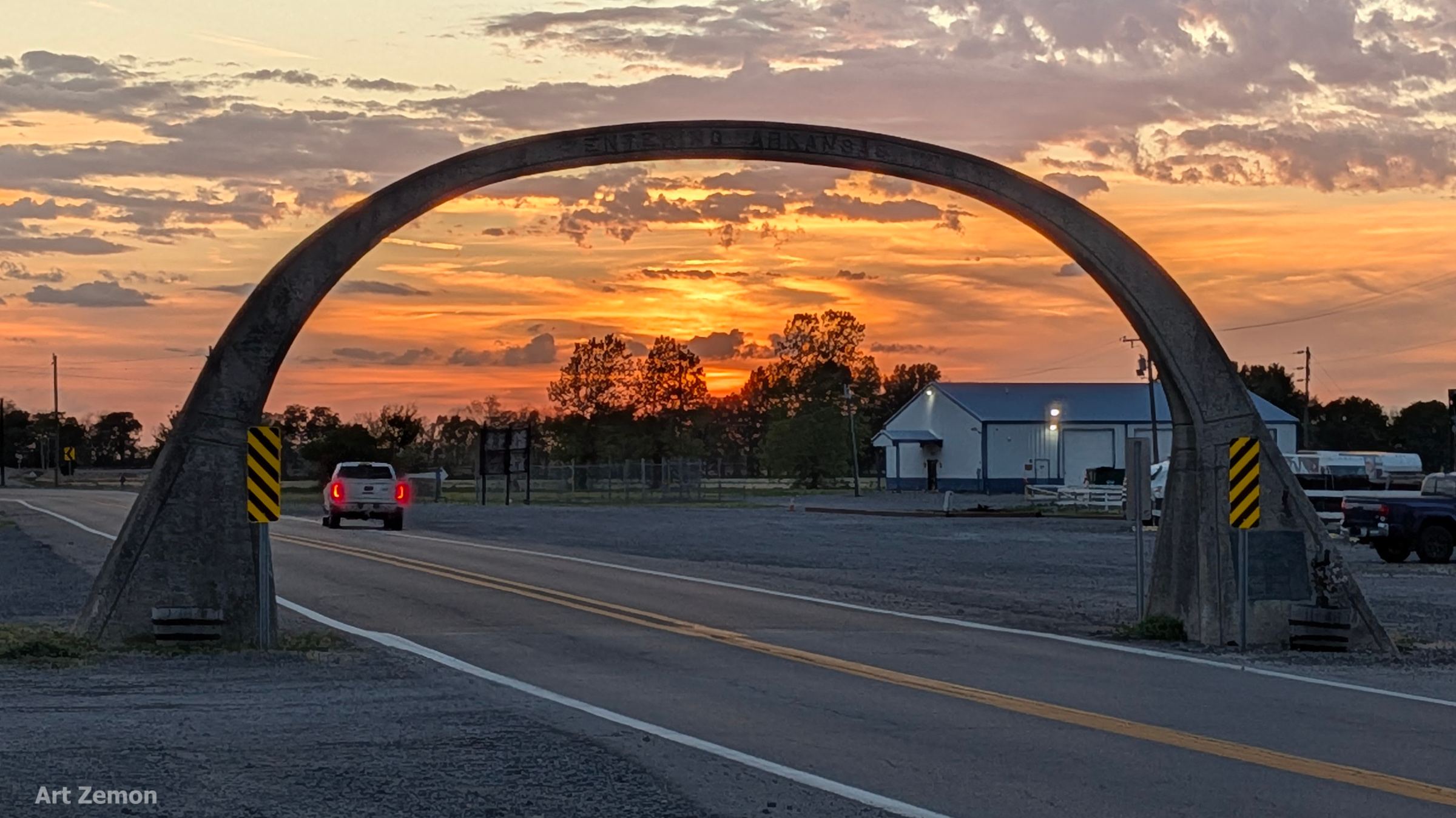 concrete arch over US 61 at the Missouri-Arkansas border. the sky in the background is a beautiful orange sunset