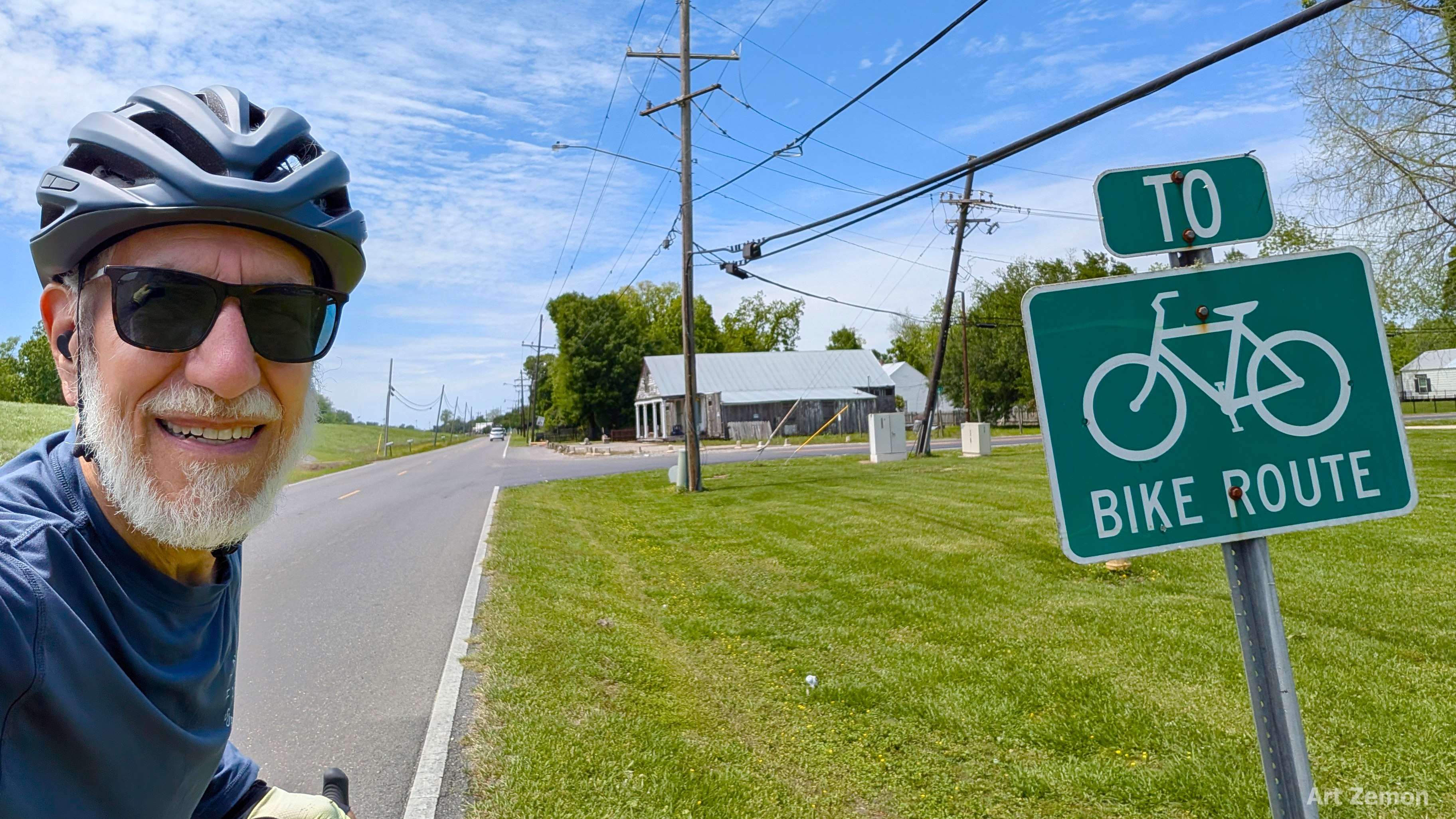 Art Zemon nest to a sign reading TO BIKE ROUTE