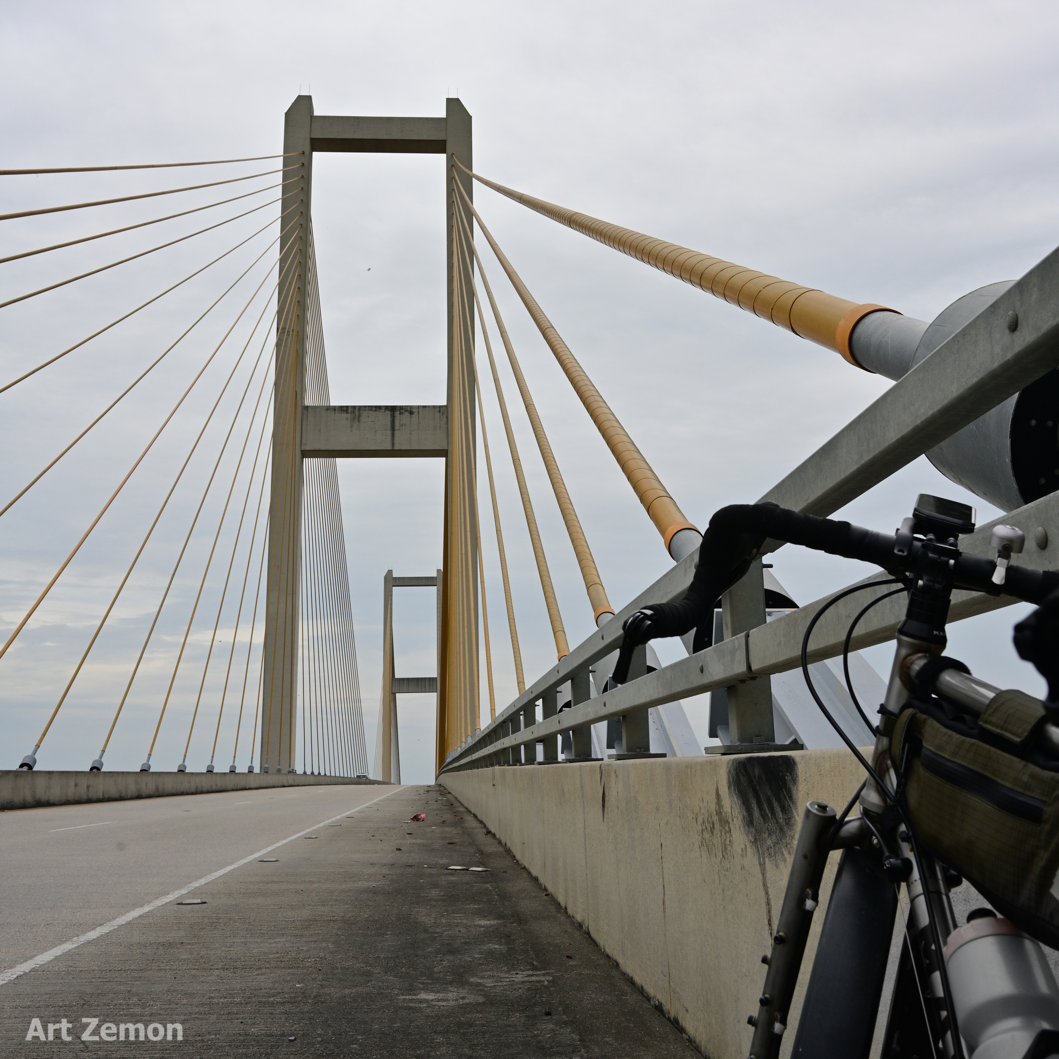 dramatic shot of the east tower of the Audubon Bridge near New Roads, LA. The yellow cables run diagonally up to the tower from the center of the frame. There is a touring bicycle parked in the foreground