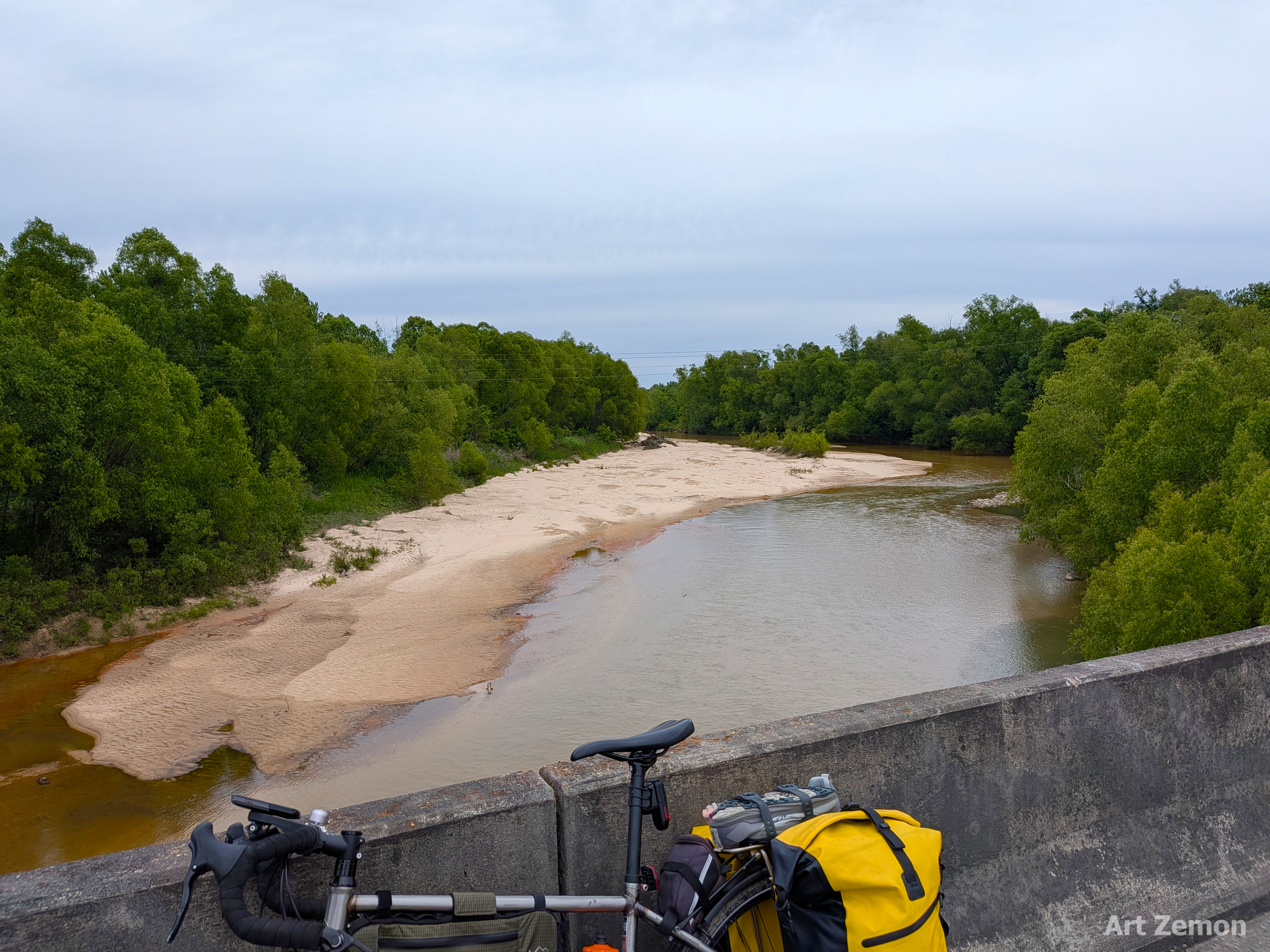 overlook from a bridge over a creek with a touring bicycle parked at the bottom of the frame